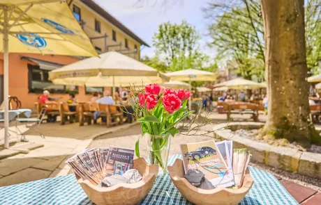 Blühende Tulpen auf einem Tisch mit Informationsbroschüren im Restaurant Kastner, ideal für einen entspannten Familienurlaub im Freien.