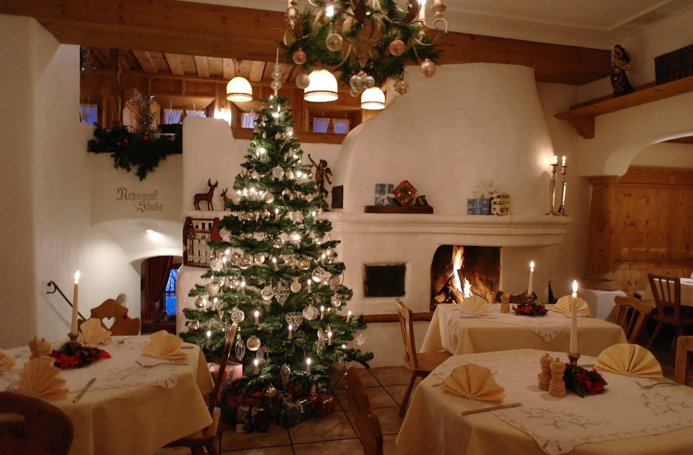 Weihnachtsbaum im Restaurant, umgeben von festlich gedeckten Tischen und warmem Licht – ideal für einen winterlichen Familienurlaub.