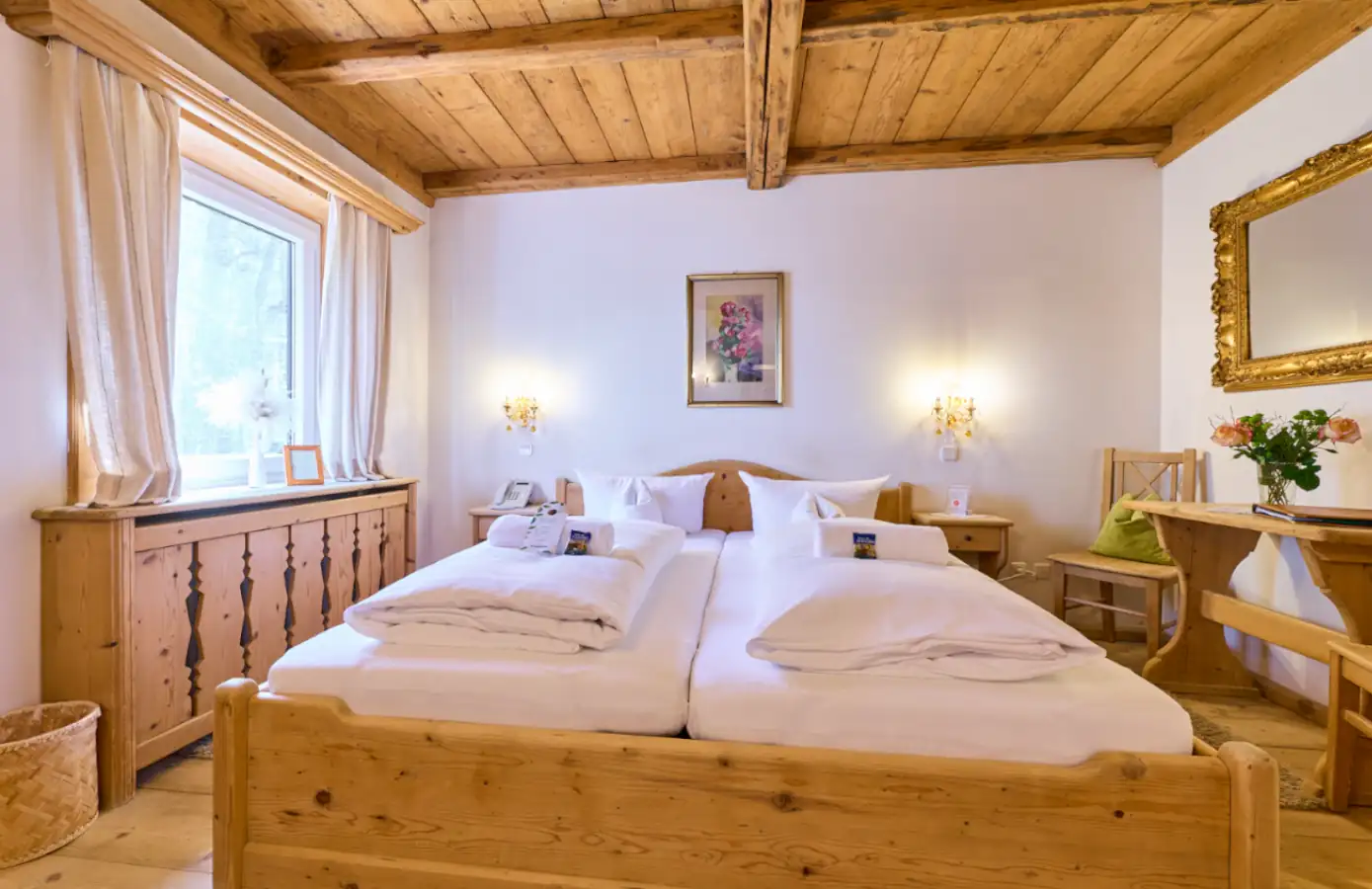 Geräumiges Zimmer im Hotel Alpenglück, ausgestattet mit zwei Betten, einem Tisch und großen Fenstern für einen idyllischen Familienurlaub.
