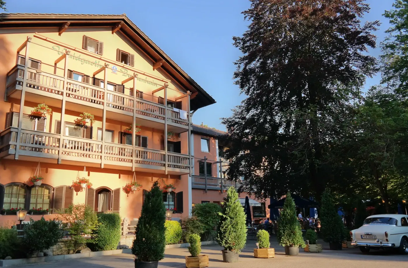 Fassade eines Hotels mit Balkon und Blumenkästen, umgeben von Bäumen, ideal für einen Familienurlaub in der Region.