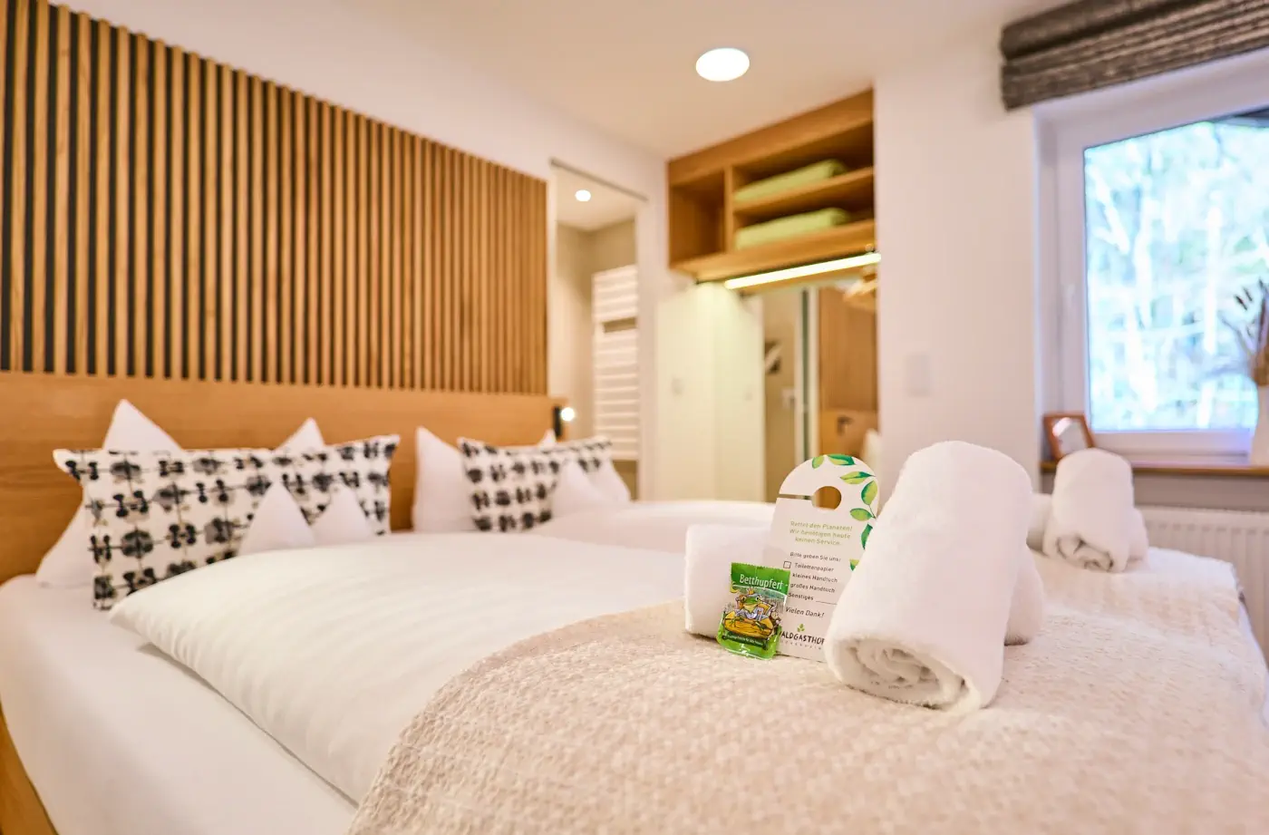 Ein gemütliches Hotelzimmer im Hotel Alpenglück, ausgestattet mit modernen Möbeln, handtuch und einem Willkommensschreiben für Gäste.