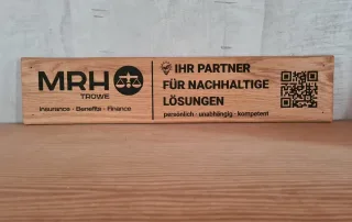 Holzschild von MRH Trowe mit Informationen zu Versicherungen, Benefits und Finanzen, sowie einem QR-Code für mehr Informationen.