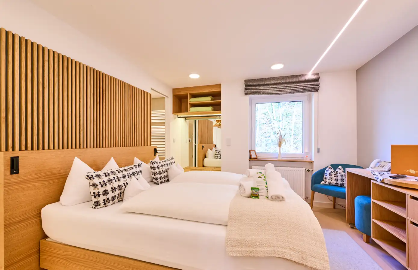 Ein modernes Hotelzimmer mit Doppelbett, gemütlicher Sitzecke und Holzdetails, ideal für einen Familienurlaub in der Natur.