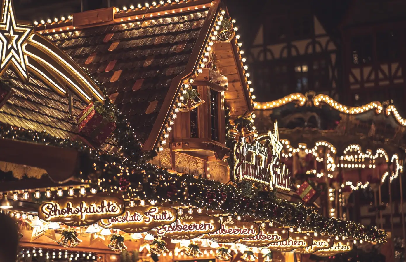 Weihnachtlicher Markt mit festlich geschmücktem Holzstand und Lichtern Festlich dekorierter Holzstand auf einem Weihnachtsmarkt, beleuchtet mit Lichtern, mit köstlichen Angeboten wie Schokoladenfrüchten und Erdbeeren.