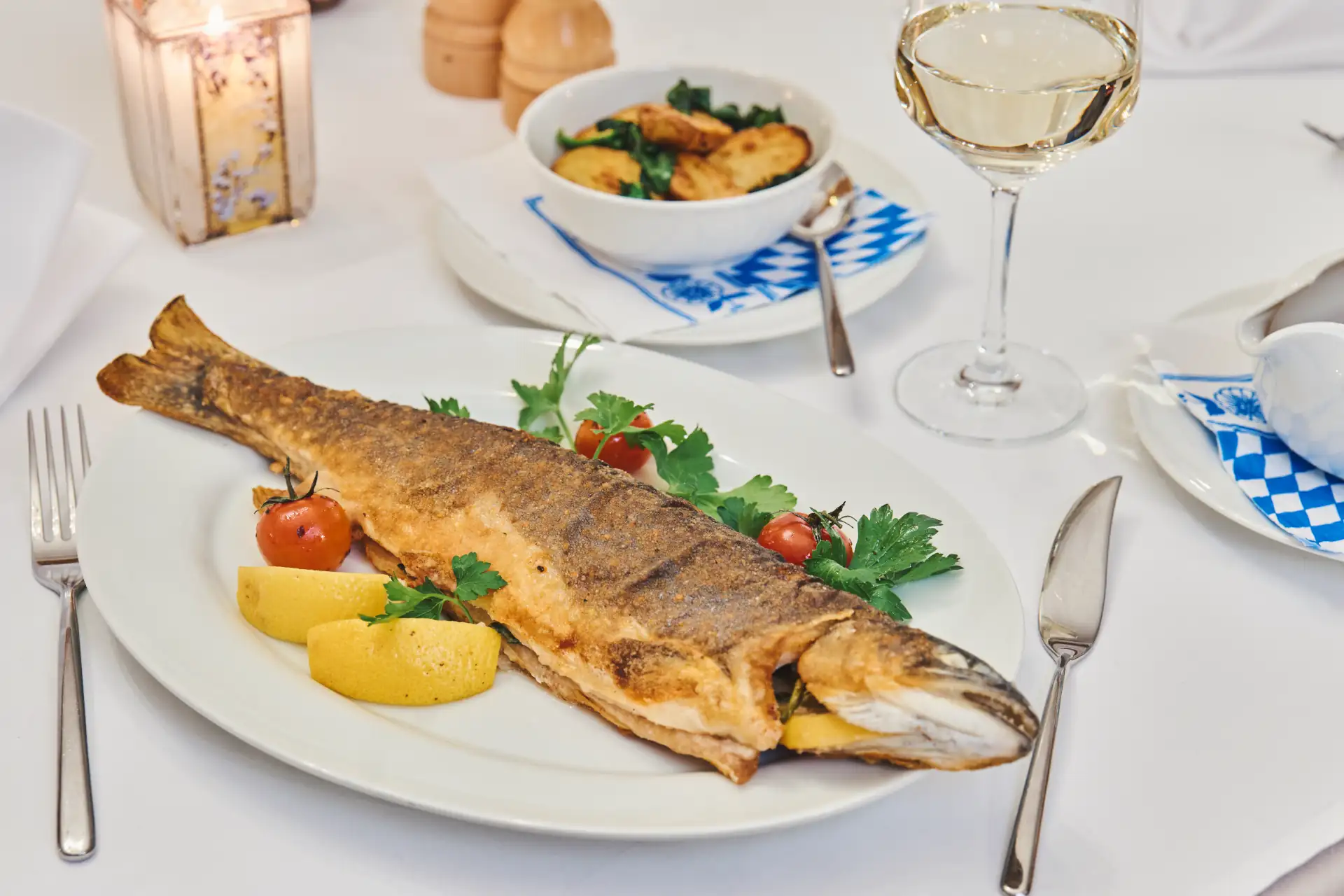 Serviert wird ein gebratener Fisch mit Beilagen wie Zitrone und Tomaten im Restaurant, ideal für Feinschmecker.