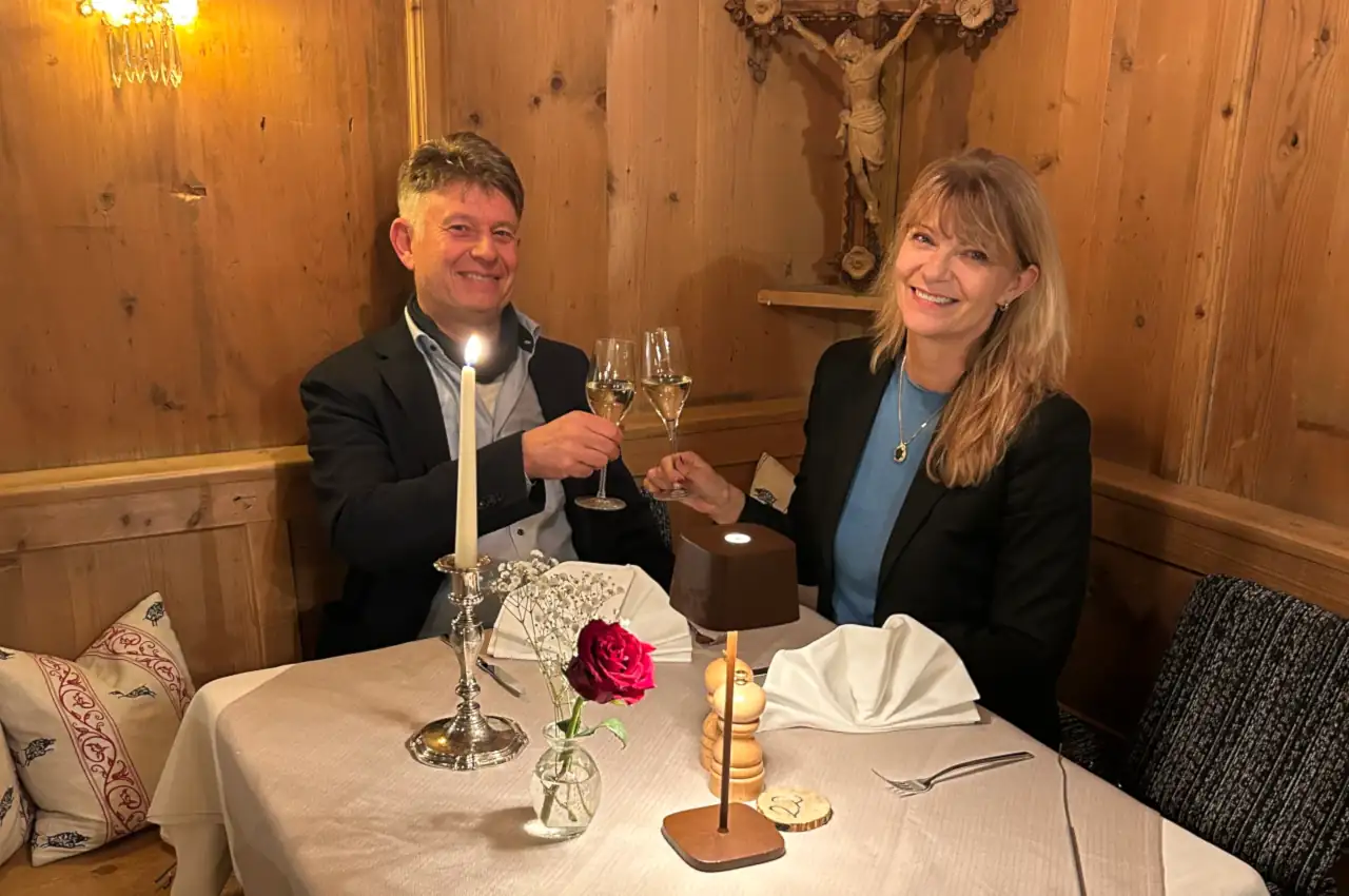 Paar genießt ein romantisches Dinner im Restaurant, mit Kerzenlicht und einer rosenroten Blume auf dem Tisch.