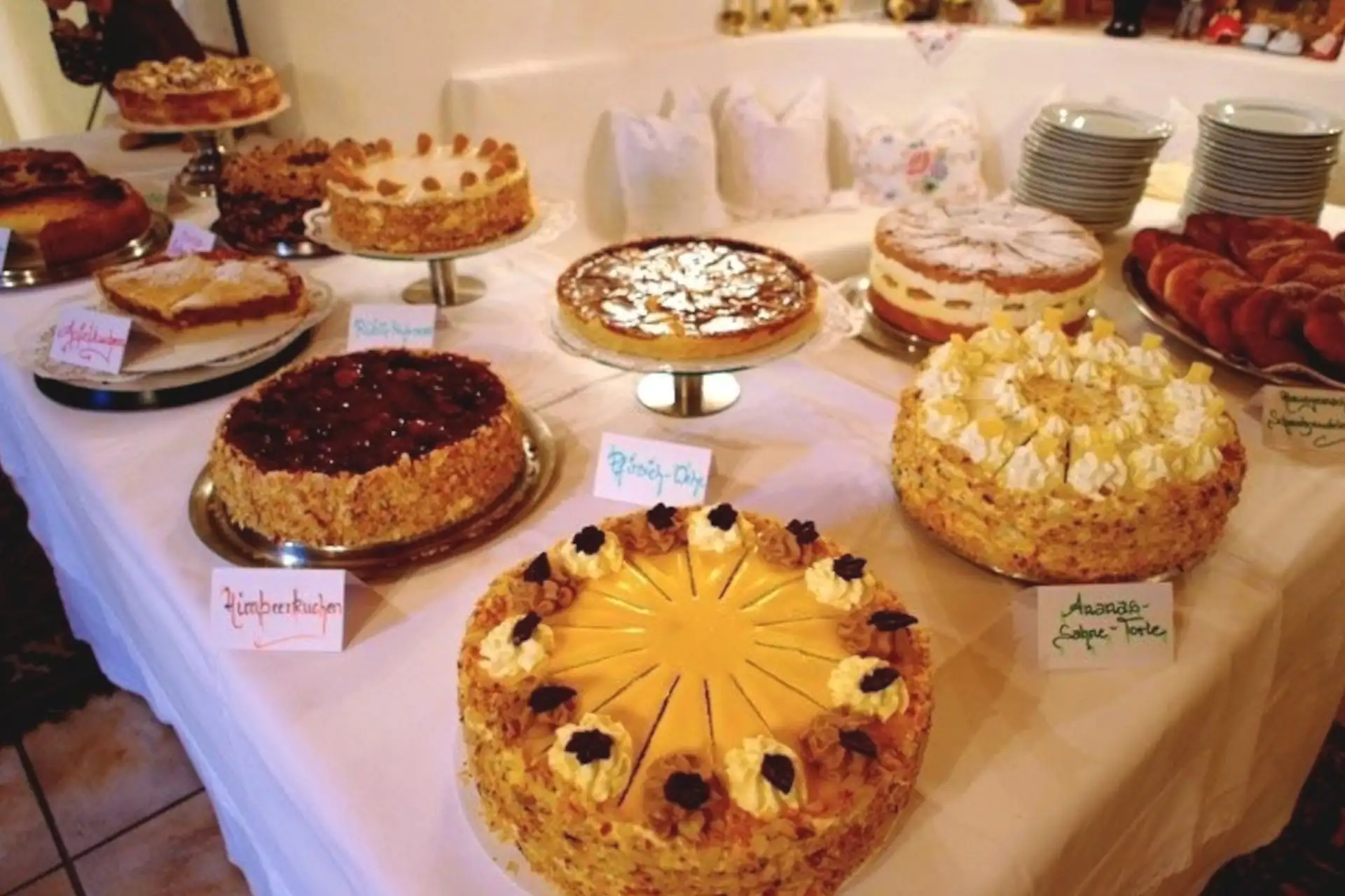 Ein Tisch mit verschiedenen Torten und Kuchen, ideal für Feiern oder einen Nachmittagskaffee im gemütlichen Ambiente.