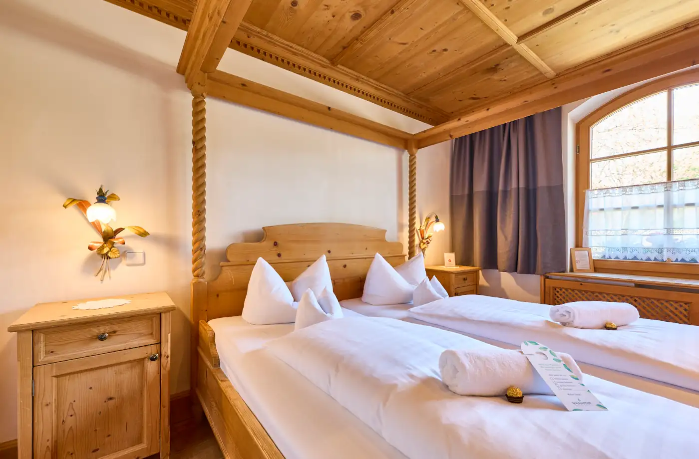 Gemütliches Doppelzimmer im Hotel Alpenglück, ausgestattet mit Holz-Möbeln, Betten und einem Fenster für Familienurlaube in der Natur.