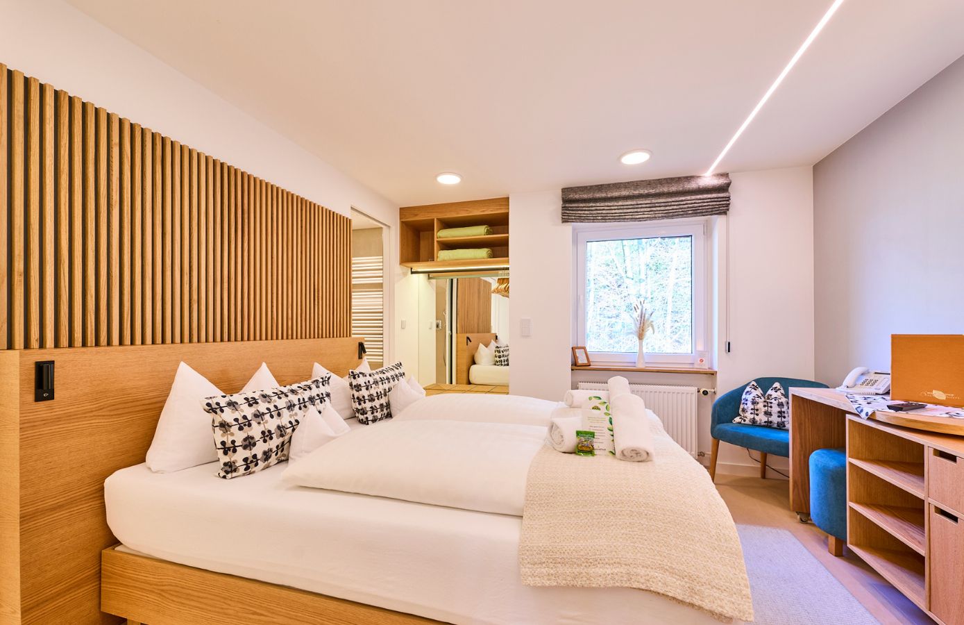Helles Zimmer im Hotel mit zwei Betten, modernem Holzwand-Design, stilvollen Kissen und einem Arbeitsplatz für einen angenehmen Aufenthalt.