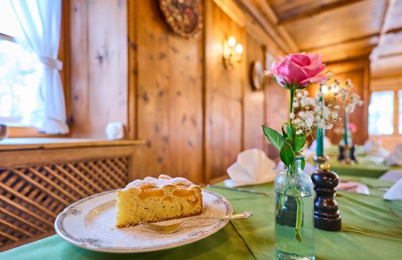 Ein Stück Obstkuchen auf einem schön gedeckten Tisch in einem Restaurant, umgeben von frischen Blumen und einem einladenden Ambiente.