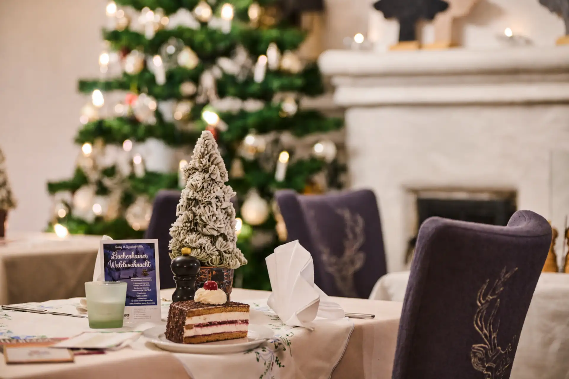 Ein festlich dekorierter Tisch im Restaurant, mit einer Torte, einem kleinen Weihnachtsbaum und stimmungsvollem Ambiente für die Feiertage.
