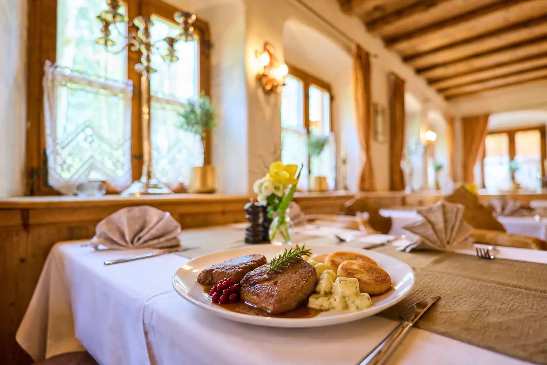 Ein köstliches Gourmetgericht im Restaurant des Hotel Alpenglück mit zartem Fleisch, Kartoffeln und frischen Kräutern, ideal für Feinschmecker.