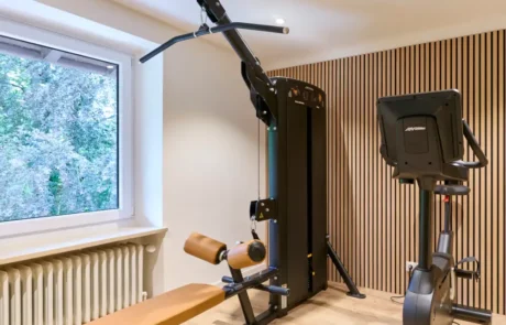 Fitnessraum im Hotel mit modernem Equipment zur Förderung der Gesundheit und Fitness Modern ausgestatteter Fitnessraum im Hotel mit einem Multifunktionsgerät und einem Fahrrad, ideal für aktiven Urlaub.