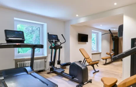 Modernes Fitnessstudio im Hotel für aktive Gäste und Gesundheitsbewusste Ein modernes Fitnessstudio im Hotel mit Laufband, Ergometer und Kraftgeräten, ideal für Fitness und Gesundheit im Urlaub.