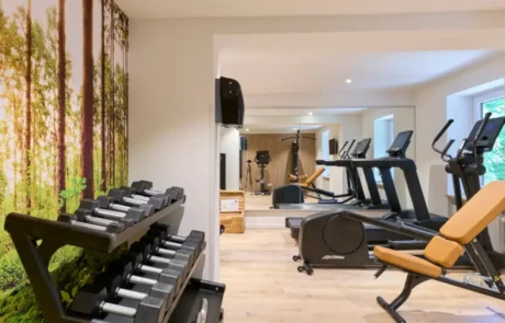 Fitnessbereich im Hotel mit modernen Geräten und einer natürlichen Atmosphäre Der Fitnessraum im Hotel bietet moderne Sportgeräte, Hanteln und eine beruhigende Wandgestaltung mit Naturmotiven für aktive Urlauber.
